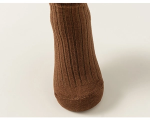 Close-up detail of dark brown knit texture and ribbed pattern on high cotton crew socks