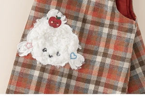 Detail of red plaid girls dress featuring plush cartoon embroidery and thick fabric