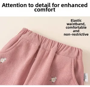Detailed macro view of pink corduroy toddler pants with elastic waistband and floral embroidery