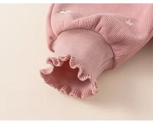 Detailed view of pink ribbed pants with ruffled cuffs and delicate white floral embroidery