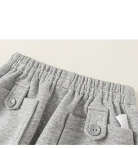 Détail du jogging gris pour enfant montrant la taille élastique et les boutons décoratifs