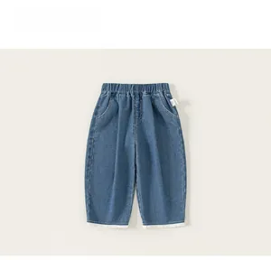 Dettaglio dei jeans da bambina con bordo in pizzo bianco e ricamo a fiocco fine