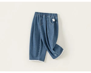 Dettaglio del pizzo bianco delicato sui pantaloni dritti in denim blu da bambina