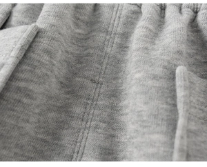 Vue macro du tissu en maille grise montrant la texture douce et les coutures du pantalon enfant