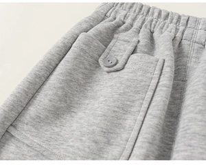Détail du jogging gris clair pour enfant avec taille élastique et poche latérale à bouton