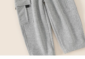 Close-up of grey kids' joggers featuring cargo side pockets and high-quality knit texture