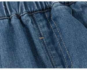 Dettaglio dell'elastico in vita con doppie cuciture gialle su jeans per bambina