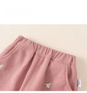 Detail view of pink girls corduroy trousers with elastic waist and white floral embroidery