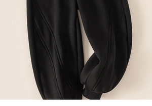 Detail of black jogger pants with vertical decorative lines and ribbed ankle cuffs