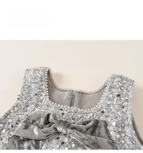 Detail of sequin girl's dress with velvet bow and elegant pearl neckline trim