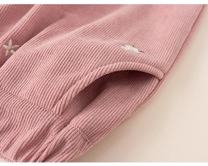 Detail of pink corduroy kids pants featuring side pocket and white daisy embroidery