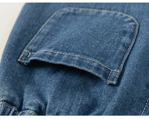 Dettaglio del tessuto denim blu con ricamo a farfalla e cuciture a doppio ago di qualità