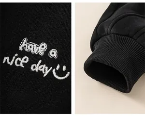 Detail of boys' black joggers featuring smile embroidery and elastic ribbed cuffs