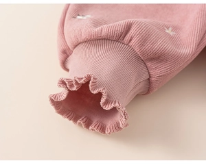 Close-up of pink knit ribbed sleeve with delicate ruffle cuff and small flower embroidery