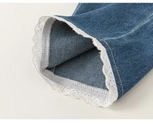 Dettaglio di pantaloni in denim per bambine con pizzo bianco e ricamo traforato