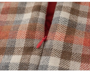 Detail view of red invisible zipper and plaid wool fabric lining on the girl's dress