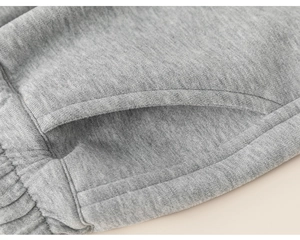 Close-up detail of grey kids sweatpants showing pocket design and elastic knit texture