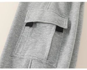 Close-up of grey kids sweatpants featuring a cargo pocket with double black straps