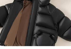 Detail of kids hooded jacket featuring glossy black fabric and cute round ear pocket