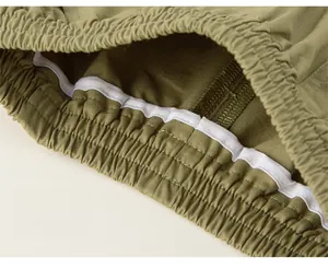 Detailed macro view of the olive green cotton twill trousers with elastic waist and stitching