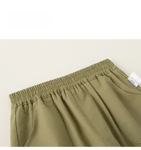 Close-up of olive green kids trousers with elastic waistband and brand woven label