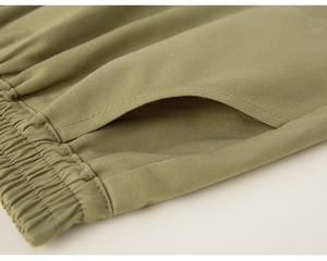 Detail of army green kid's trousers showing elastic waistband and side pocket stitching