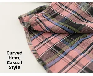 Detail view of pink and green plaid shirt featuring a curved casual hem and cotton texture