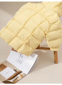 Detail of light yellow hooded down jacket with square quilting on a wooden stool