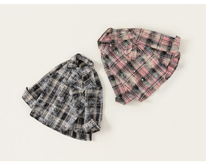 Flat lay detail of two plaid cotton shirts with embroidered need text and soft texture
