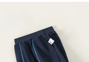 Detail of kids navy sports trousers featuring elastic waist and reflective pocket trim