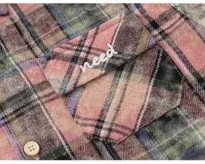 Detail of pink and grey plaid shirt featuring soft brushed texture and need embroidery