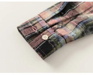 Detail shot of multicolor plaid shirt cuff with soft flannel texture and white resin button