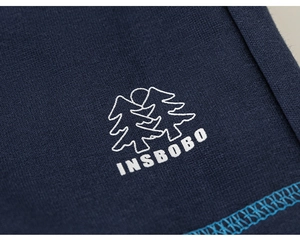 Close-up of navy blue knit fabric with embroidered INSBOBO logo and fine stitching