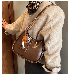 Dettaglio della borsa a spalla in pelle marrone scuro con ciondolo decorativo di tendenza
