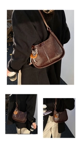 Dettaglio borsa a sella marrone scuro con fiocco leopardato e ciondolo a pompon arancio