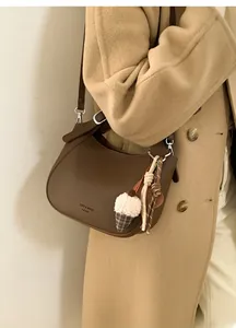 Detail of dark brown leather crossbody bucket bag with silver hardware and pendant charm