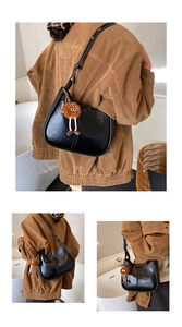 Dettaglio borsa a secchiello hobo nera lucida con un simpatico ciondolo mostro di peluche