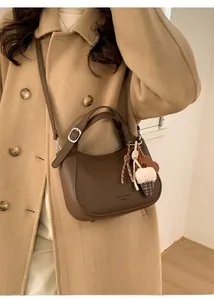 Detail of dark brown pebble leather crescent bag worn with a chic camel wool coat