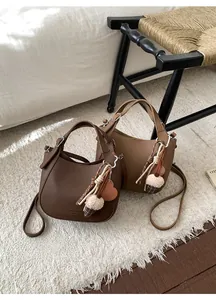 Detailed close-up of litchi texture faux leather bucket bags with plush pompom charms