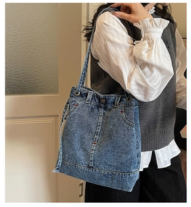 Detail of vintage denim shoulder bag featuring classic jeans pockets and red stitching