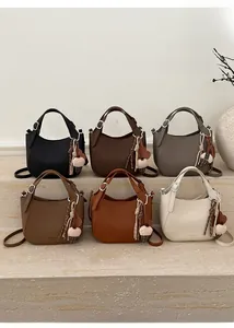 Macro display of half-moon leather bucket bags in six colors with pompom and tassel charms
