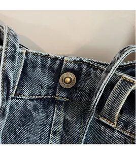 Detail shot of vintage washed denim bag featuring a premium brass fashion button