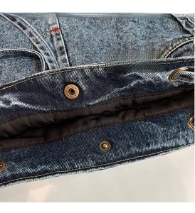 Close-up of dark blue denim bag showing gold stitching and star-embossed metal snap button