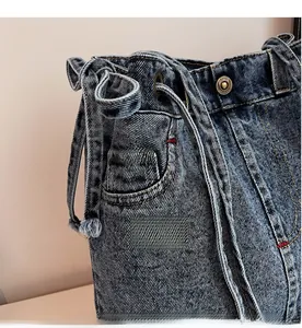 Detail of blue denim tote bag showing drawstring closure and contrast stitching