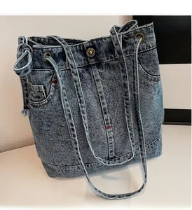 Close-up of deep blue washed denim tote bag with side pockets and metal rivets