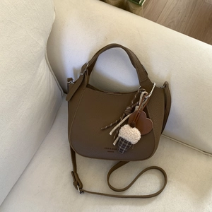 Detailed view of brown litchi grain leather bucket bag with cute plush ice cream charms
