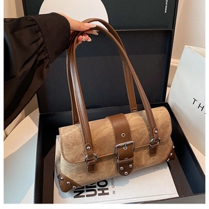 Detailed close-up of retro brown shoulder bag with suede texture and metal rivet accents
