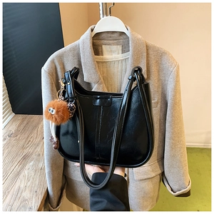 Borsa a spalla a mezzaluna nera lucida con ciondolo a peluche marrone su blazer beige