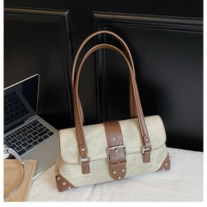 Detail of vintage beige motor bag with brown leather straps and metallic rivets on the desk