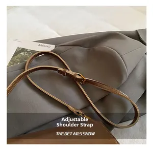Dettaglio della tracolla regolabile in pelle marrone con fibbia dorata per borsa a mano